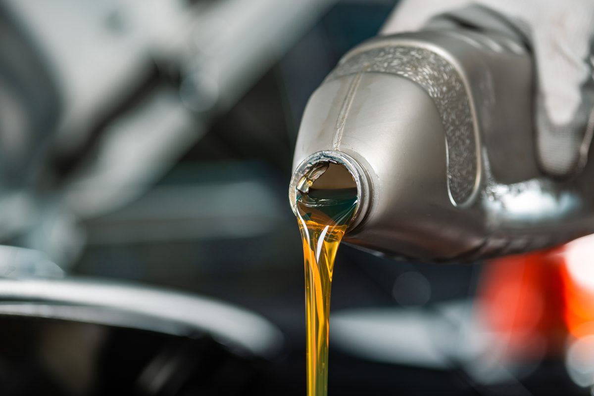 Mechanic pouring Prime Axis motor oil into an engine